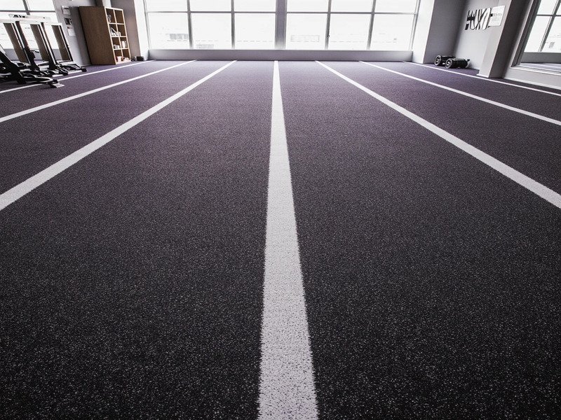 Zawody Hyrox z zawodnikami pchającymi sanki po murawie